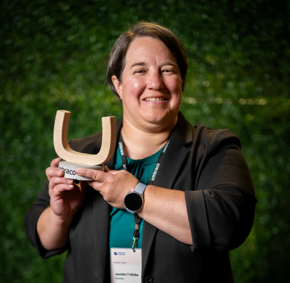 A photo of Jen Wolke holding the Umbraco logo statue