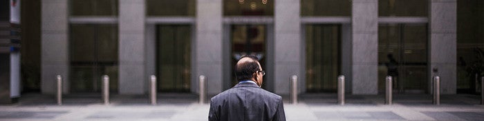 man in suit standing in front of a large building