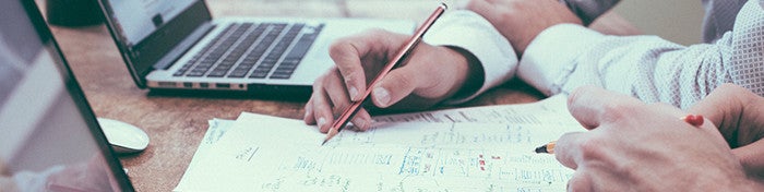 group working at a table with paper, pencils, and laptops